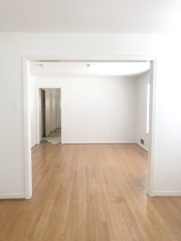 unfurnished dining room of a small cottage with white walls and light hardwood floors