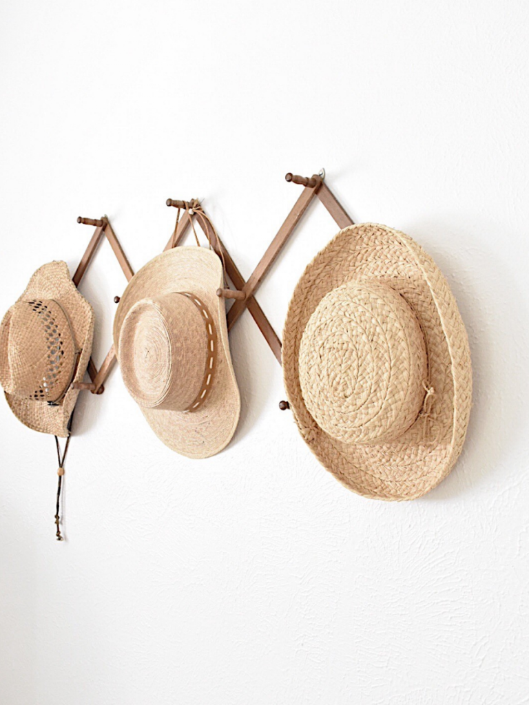 3 straw hats hanging on vintage wall rack