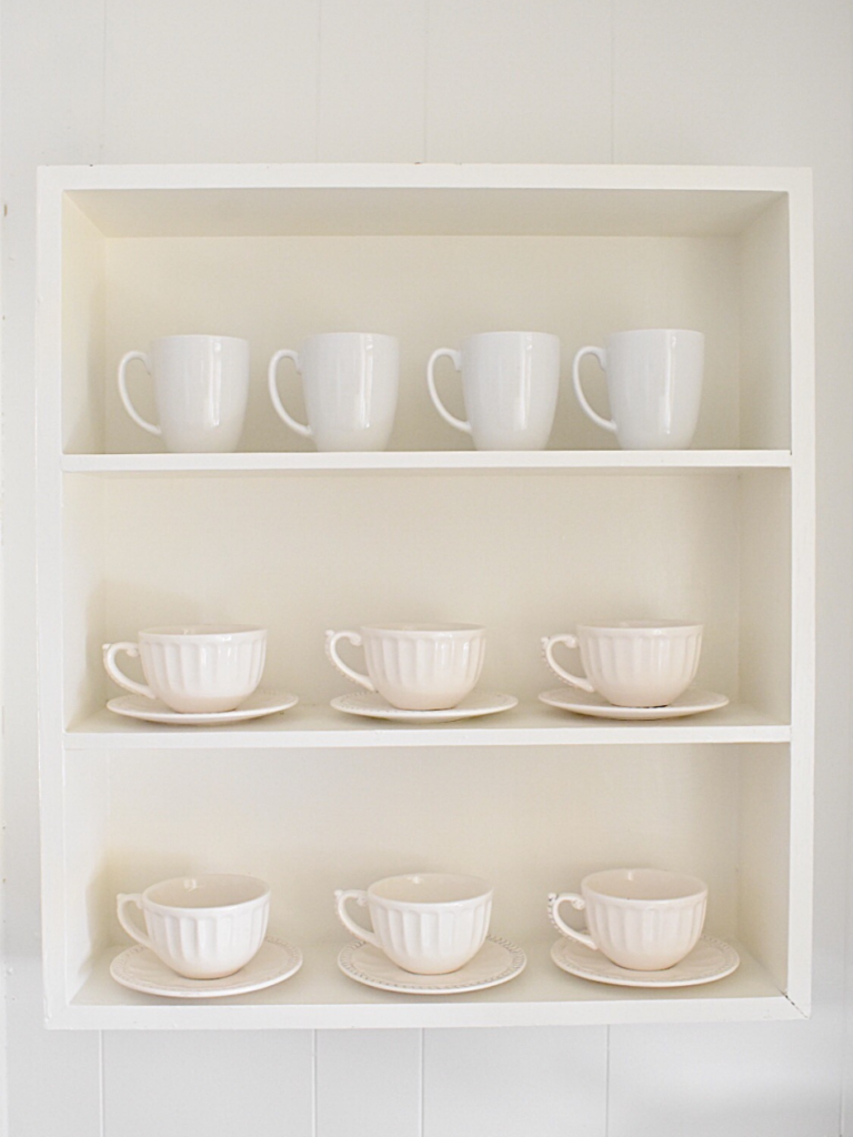 white open shelf with 3 shelves and white mugs and saucers