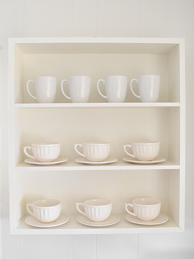 white open shelf with 3 shelves and white mugs and saucers 