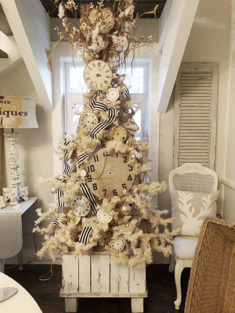 cream vintage christmas tree decorated with vintage clock faces in a white vintage planter box christmas tree stand