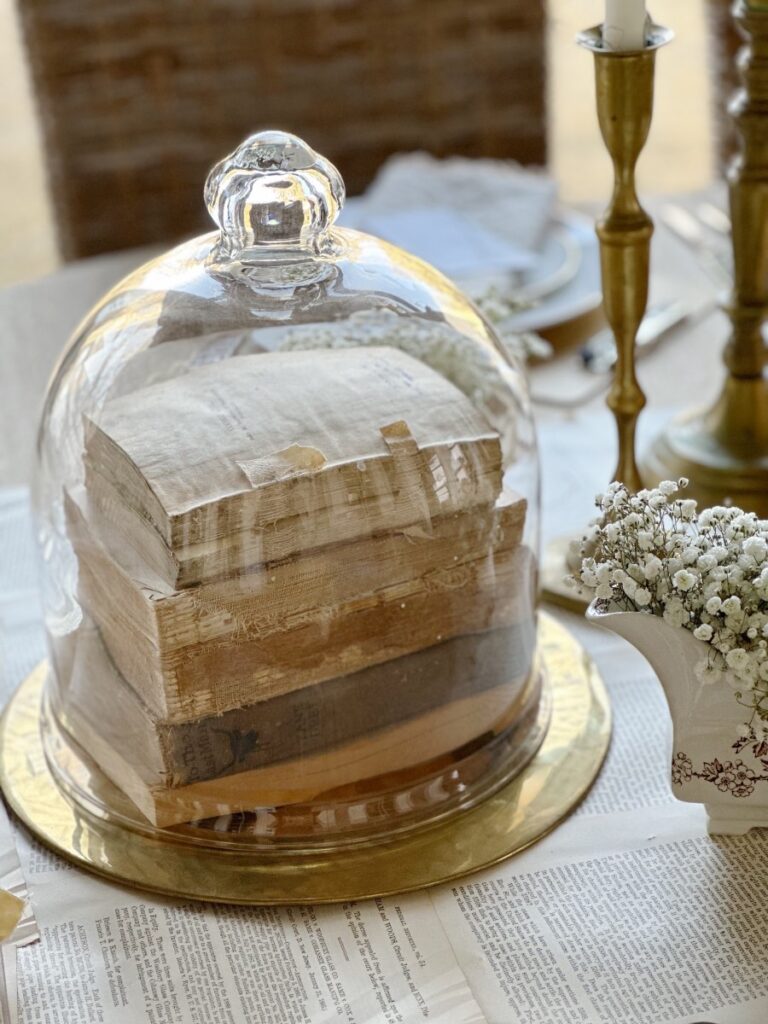 stack of vintage books under glass cloche on brass tray