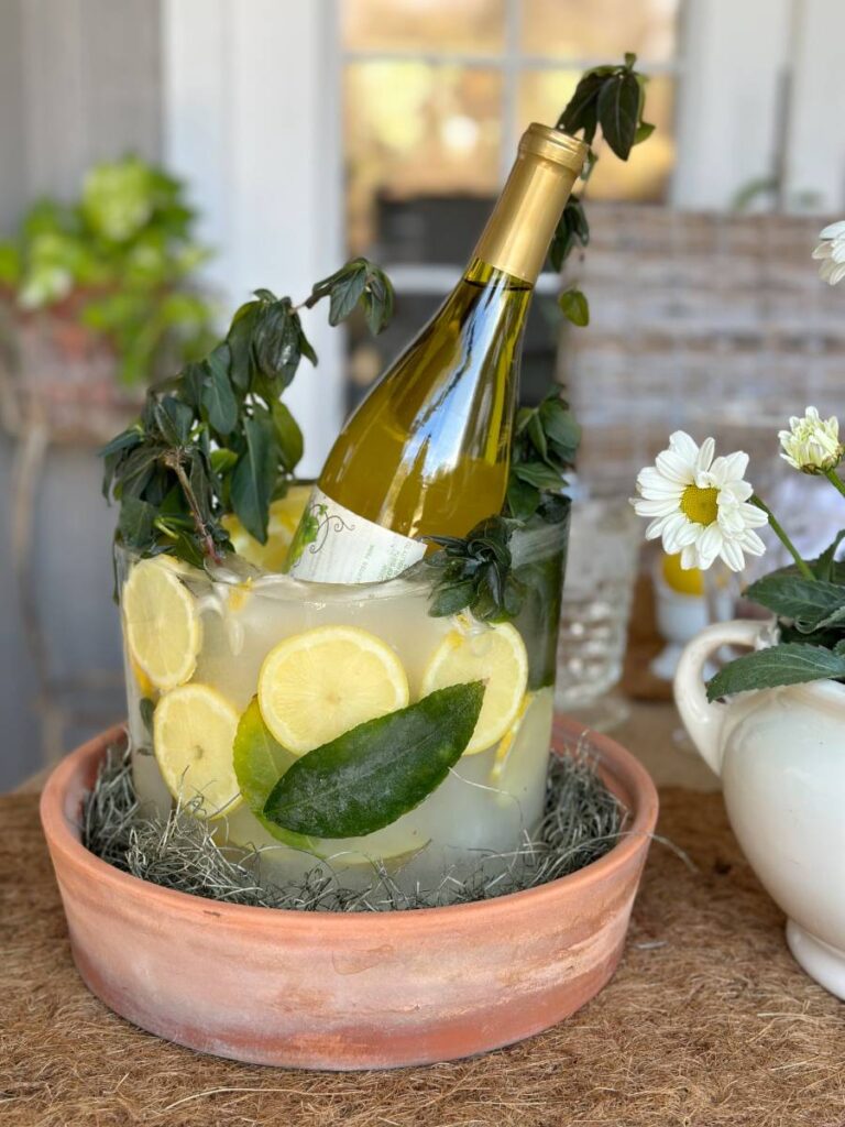 ice bucket made with fresh lemon slices lemon leaves and lemon blooms standing in terra cotta plant tray bottle of wine insides