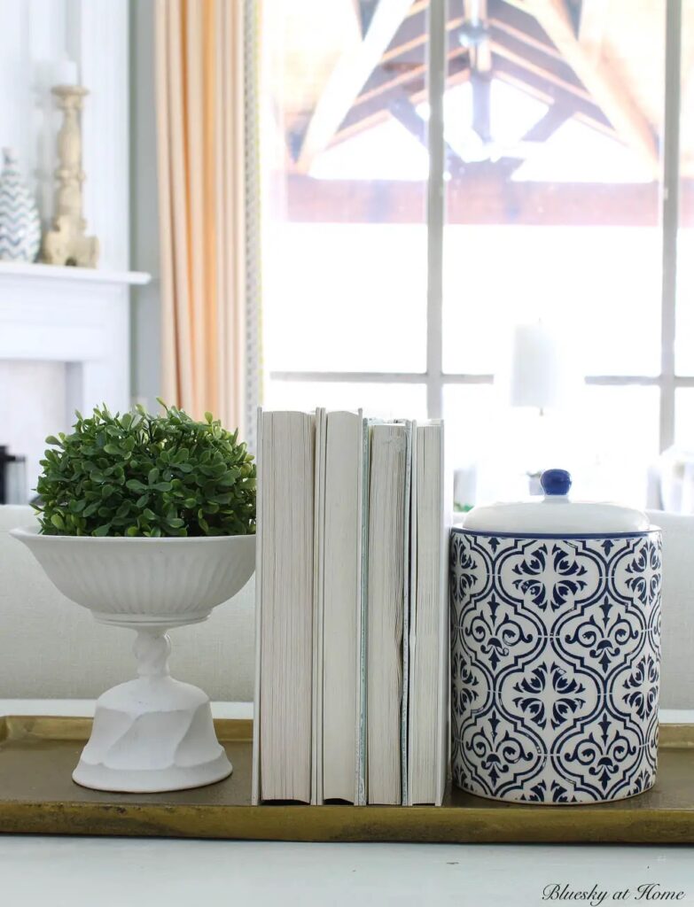 blue and white spring vignette white books blue and white jar white vase with topiary ball